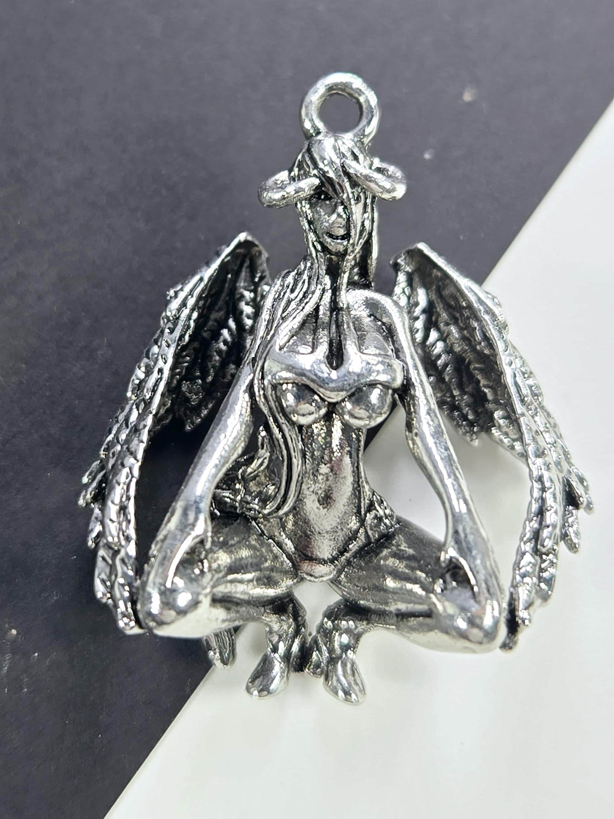 A silver-colored metal charm in the shape of a bird, with intricate details and a textured appearance.