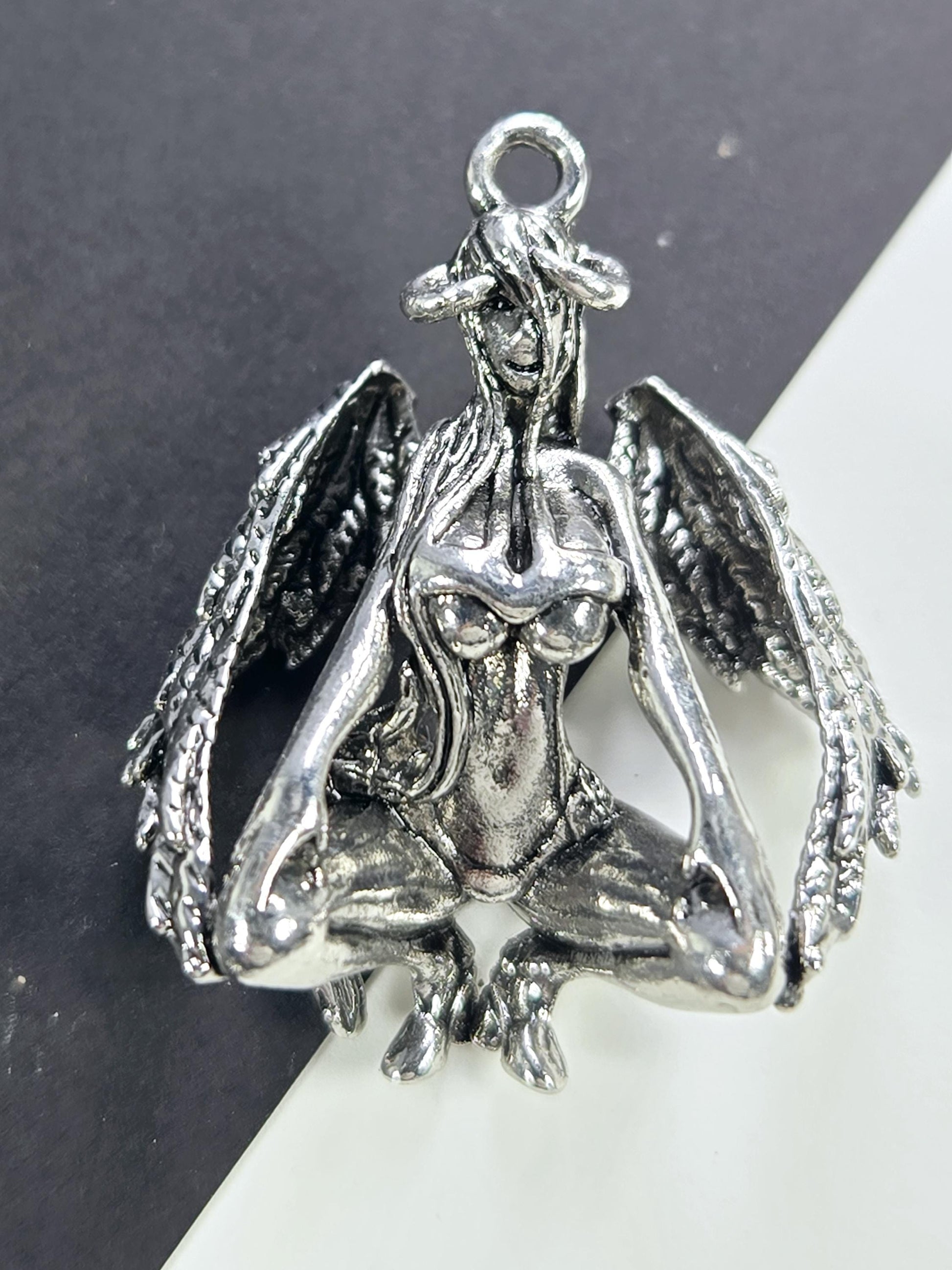 A silver-colored metal charm in the shape of a bird, with intricate details and a textured appearance.