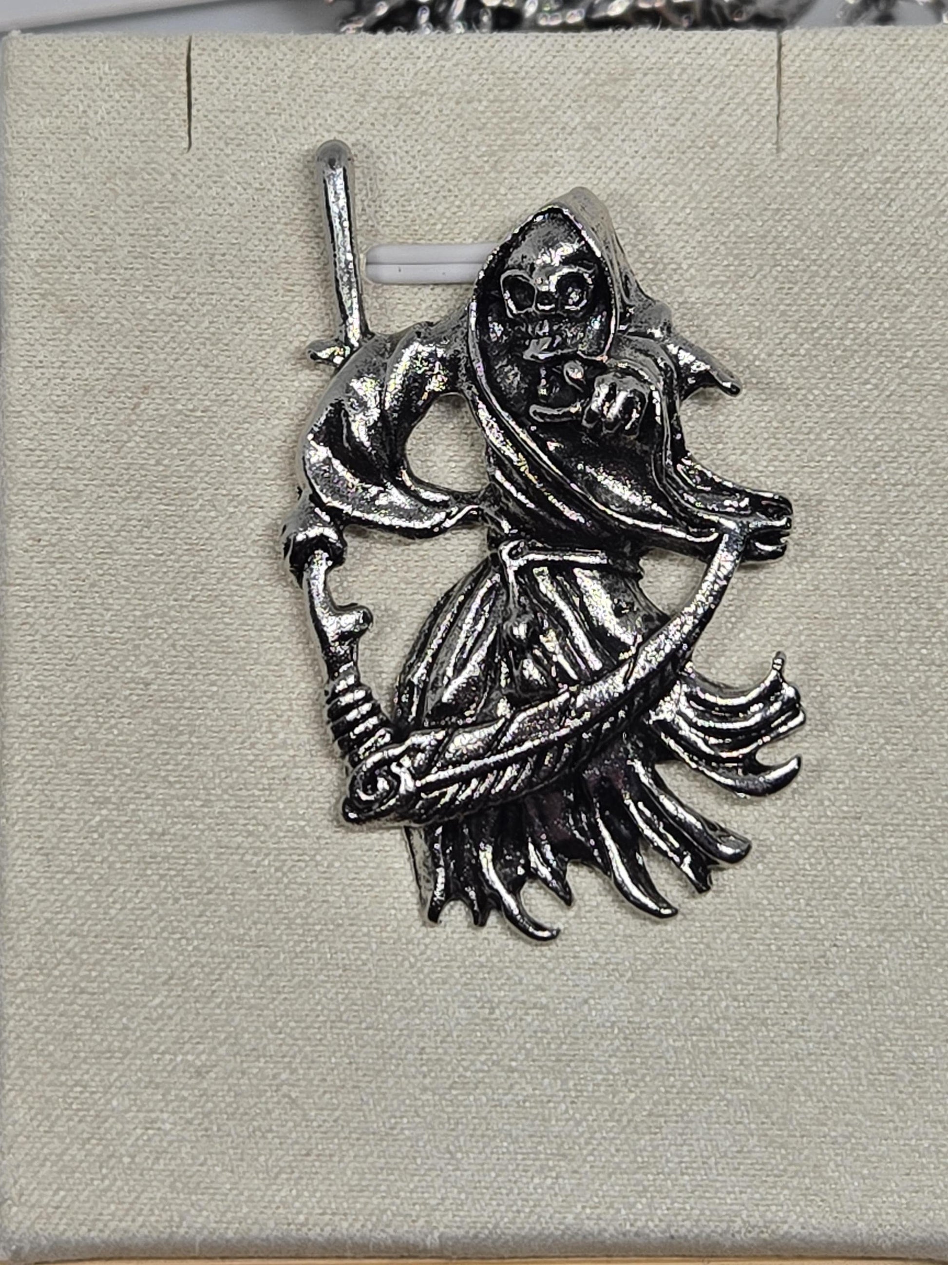 a silver brooch with an intricate design, including a fish and a skull-like figure.
