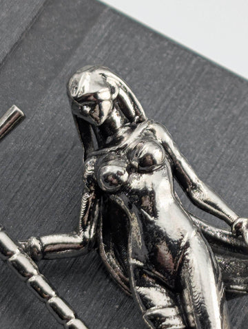 A close-up view of a shiny, metallic sculpture depicting a female figure with a flowing, draped figure.