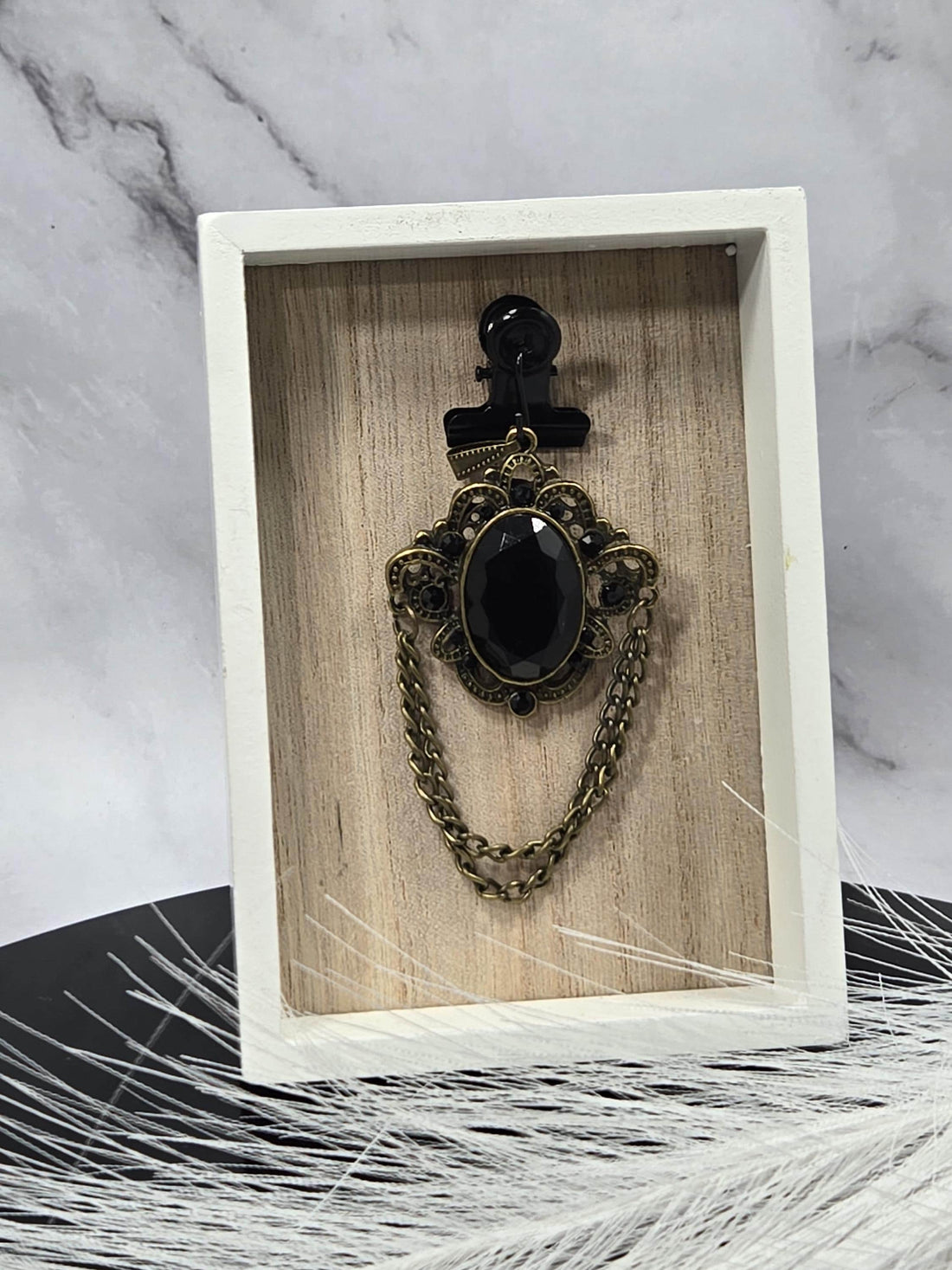 a close-up view of a decorative piece with a black gemstone and a gold chain.