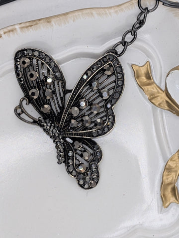 A decorative butterfly-shaped pendant with intricate metalwork and sparkling gemstones.