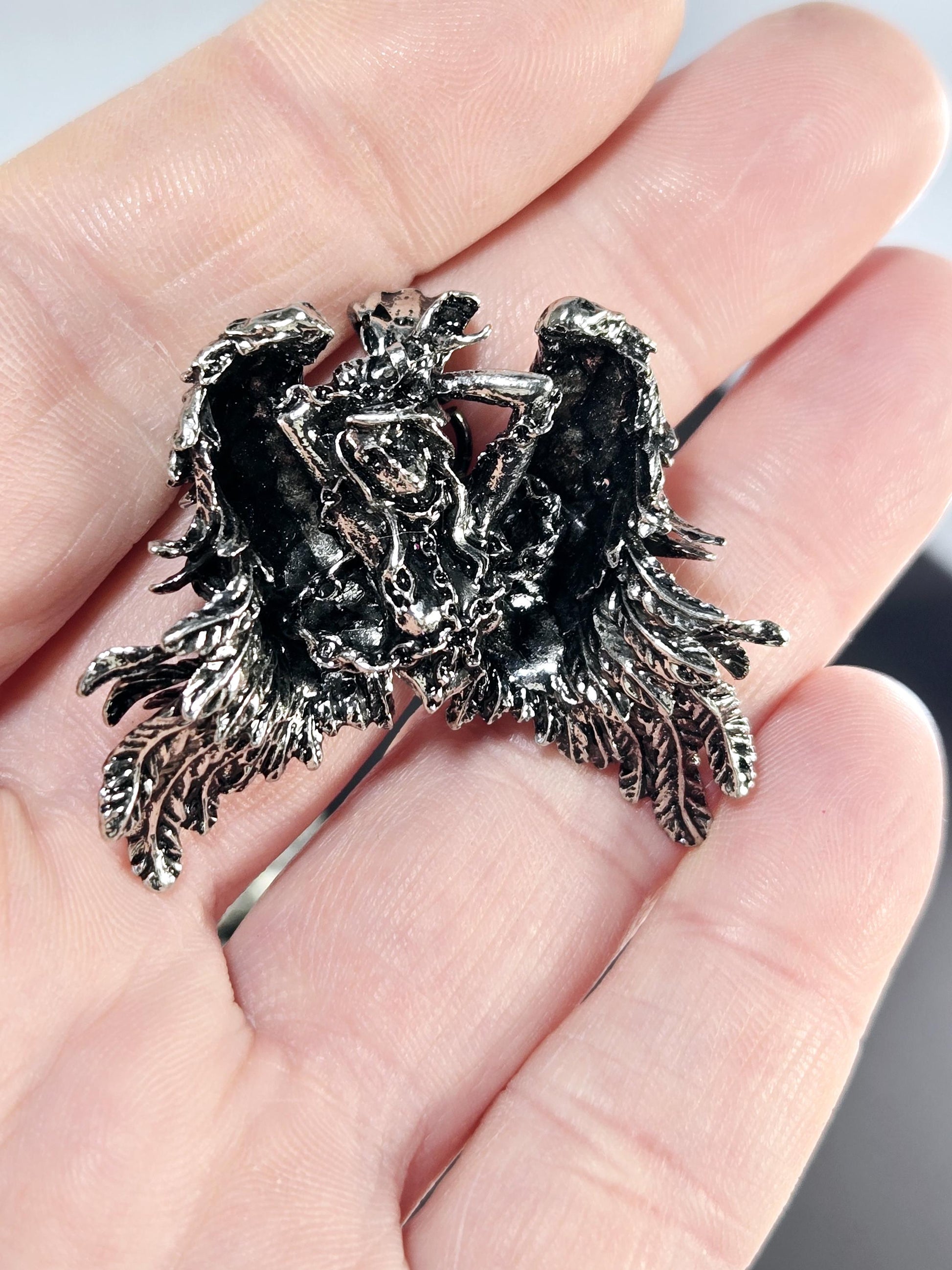 A close-up image of a person's hand holding a small, intricately designed metal object resembling a dragon or mythical creature.
