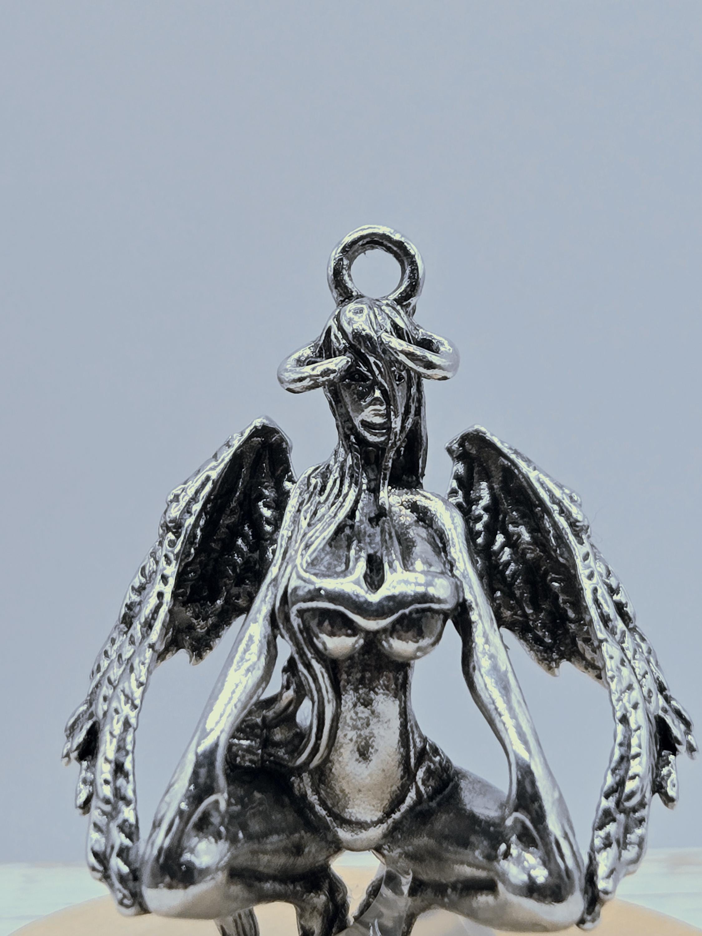 A silver metal sculpture of a winged creature with intricate details and a metallic sheen.