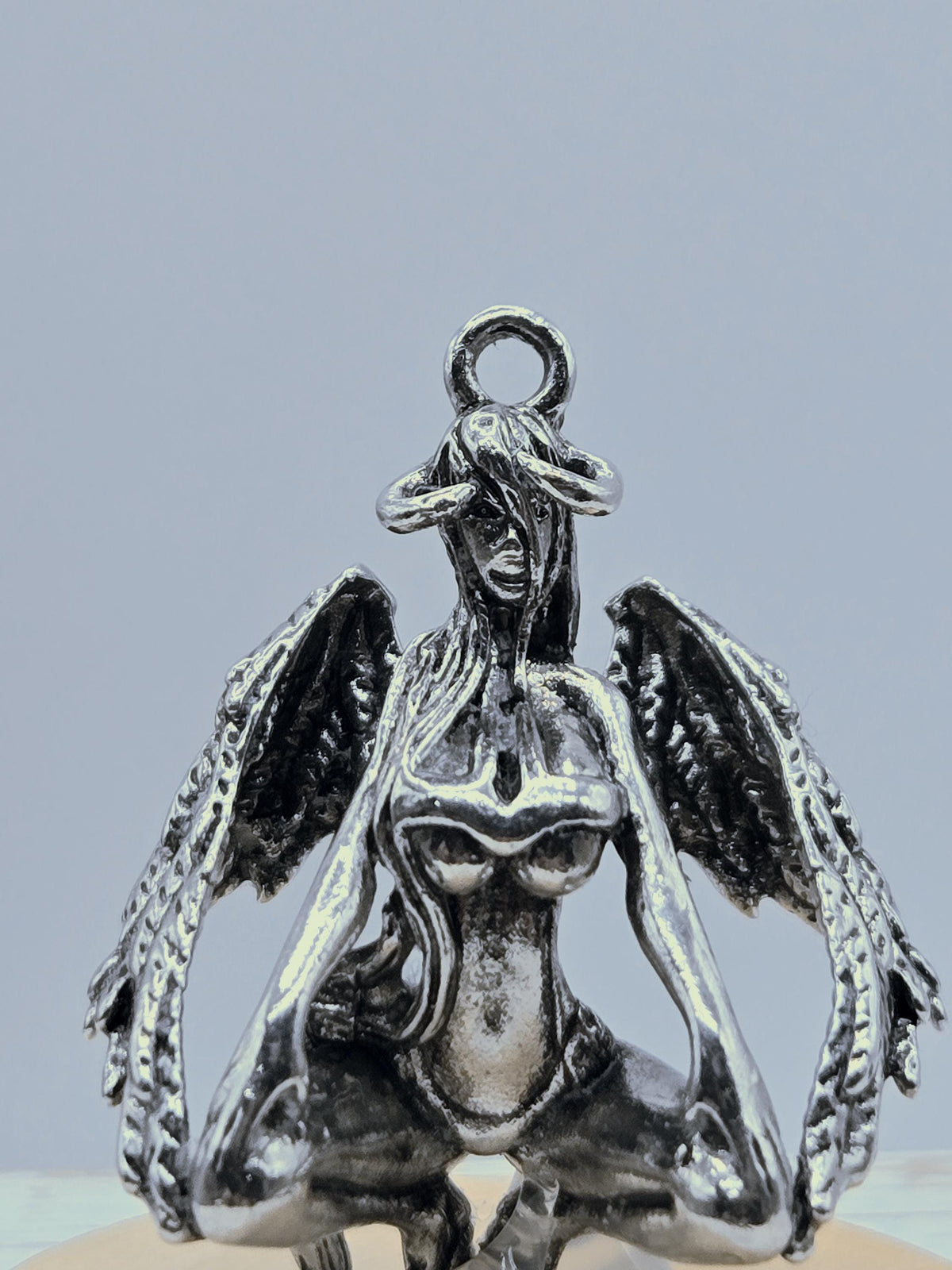 A silver metal sculpture of a winged creature with intricate details and a metallic sheen.