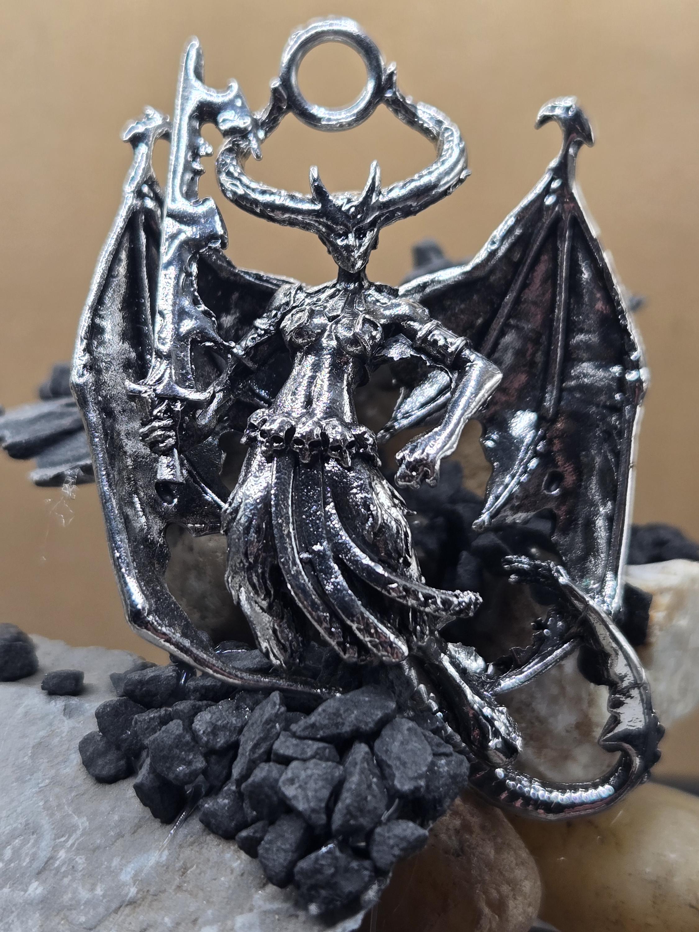 A detailed metal dragon sculpture with intricate details and a metallic sheen, resting on a bed of small rocks.