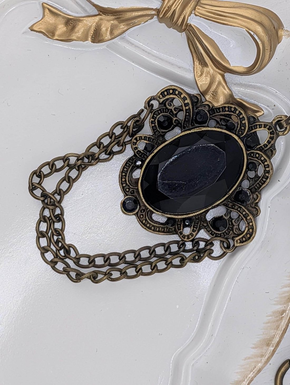 a close-up view of a decorative piece with a black gemstone and a gold chain.