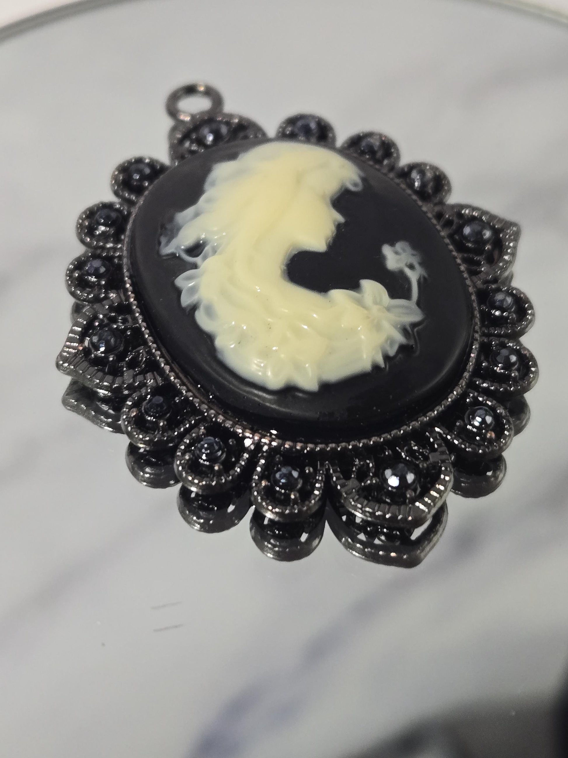 A close-up image of a decorative black and white pendant with a floral design.