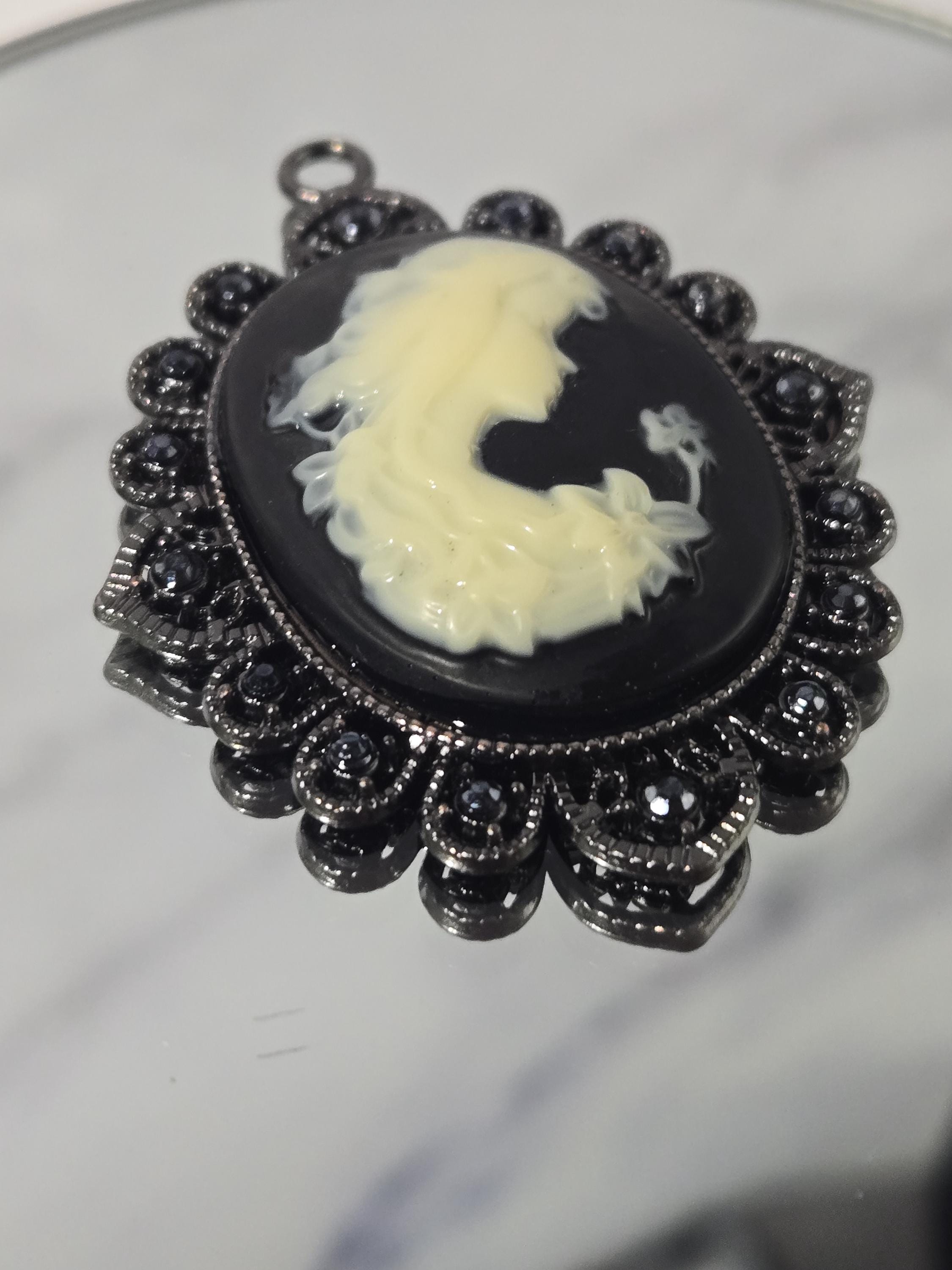 A close-up image of a decorative black and white pendant with a floral design.