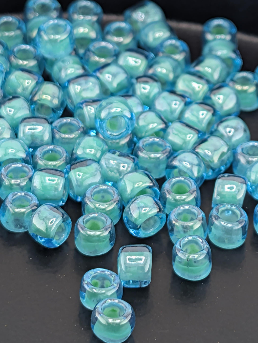 a collection of small, clear glass beads in various shades of blue, scattered on a dark surface.