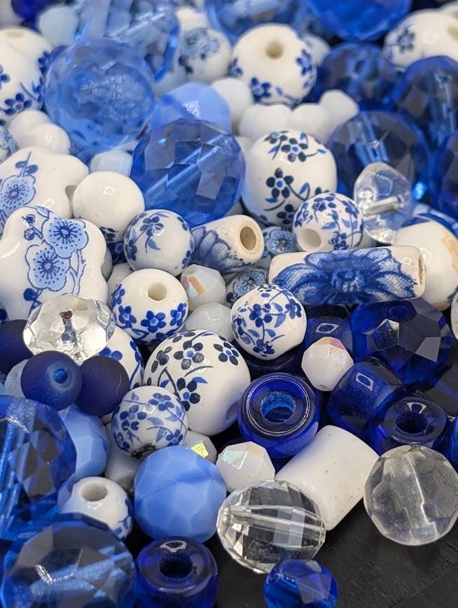 The image is a collection of various blue and white beads, including glass beads and ceramic beads, arranged in a visually appealing manner.