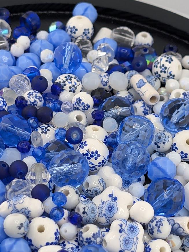 The image is a close-up of a collection of blue and white beads, including glass beads and ceramic beads, arranged in a visually appealing manner.