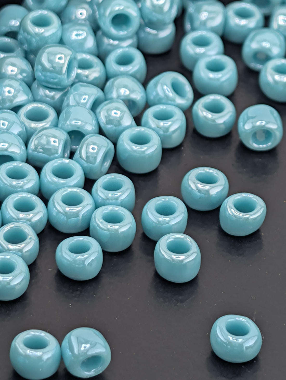 a collection of small, light blue beads scattered on a dark surface.