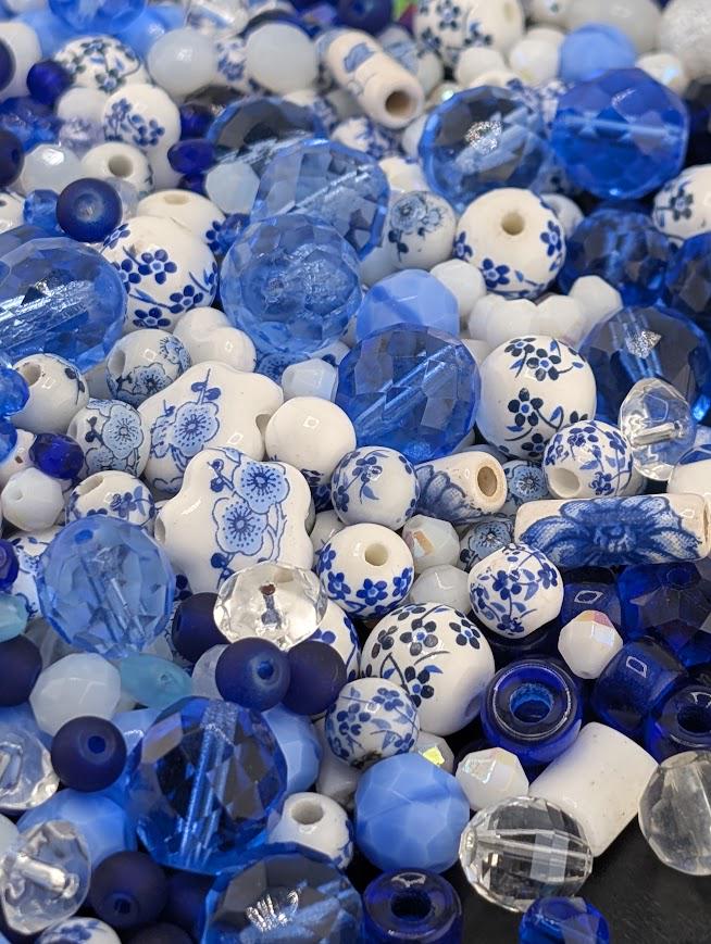 The image is a collection of various blue and white beads, including glass beads and ceramic beads, scattered together.