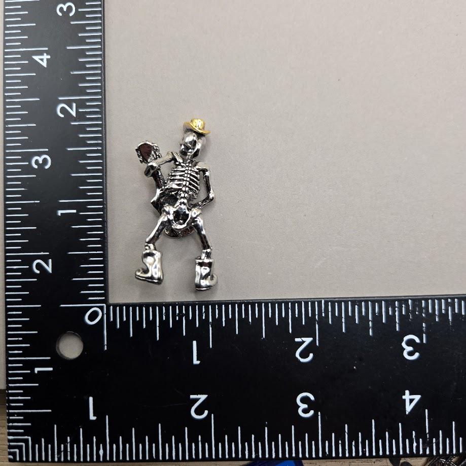 A small silver skeleton figure is placed next to a ruler on a gray surface.