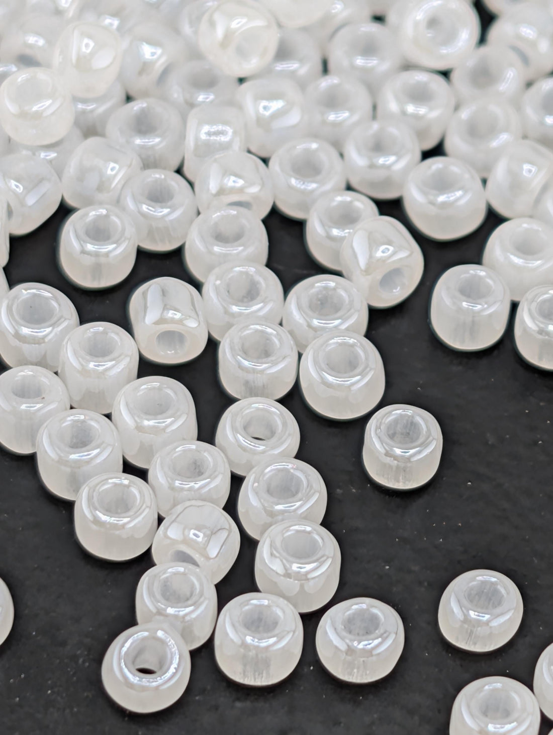 a collection of small, clear beads scattered on a dark surface.