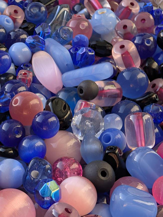 The image is a close-up of a collection of colorful glass beads, including various shades of blue, pink, and purple.