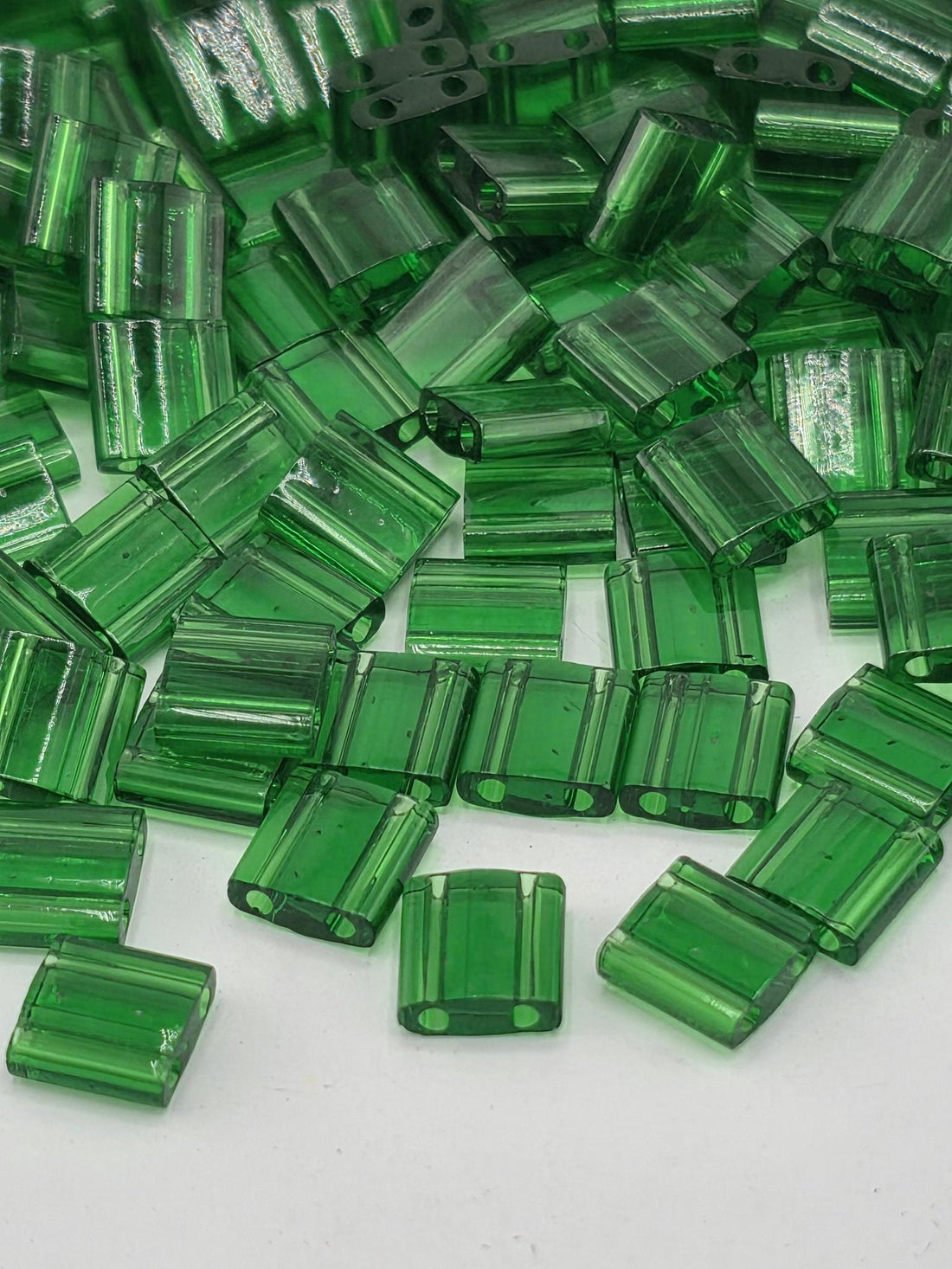 numerous green glass beads scattered across a white background.