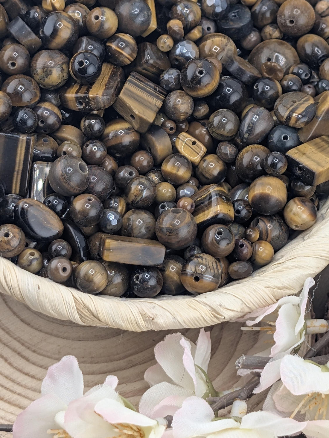 The image is a close-up of various beads and gemstones, including tiger eye beads, arranged in a visually appealing manner.