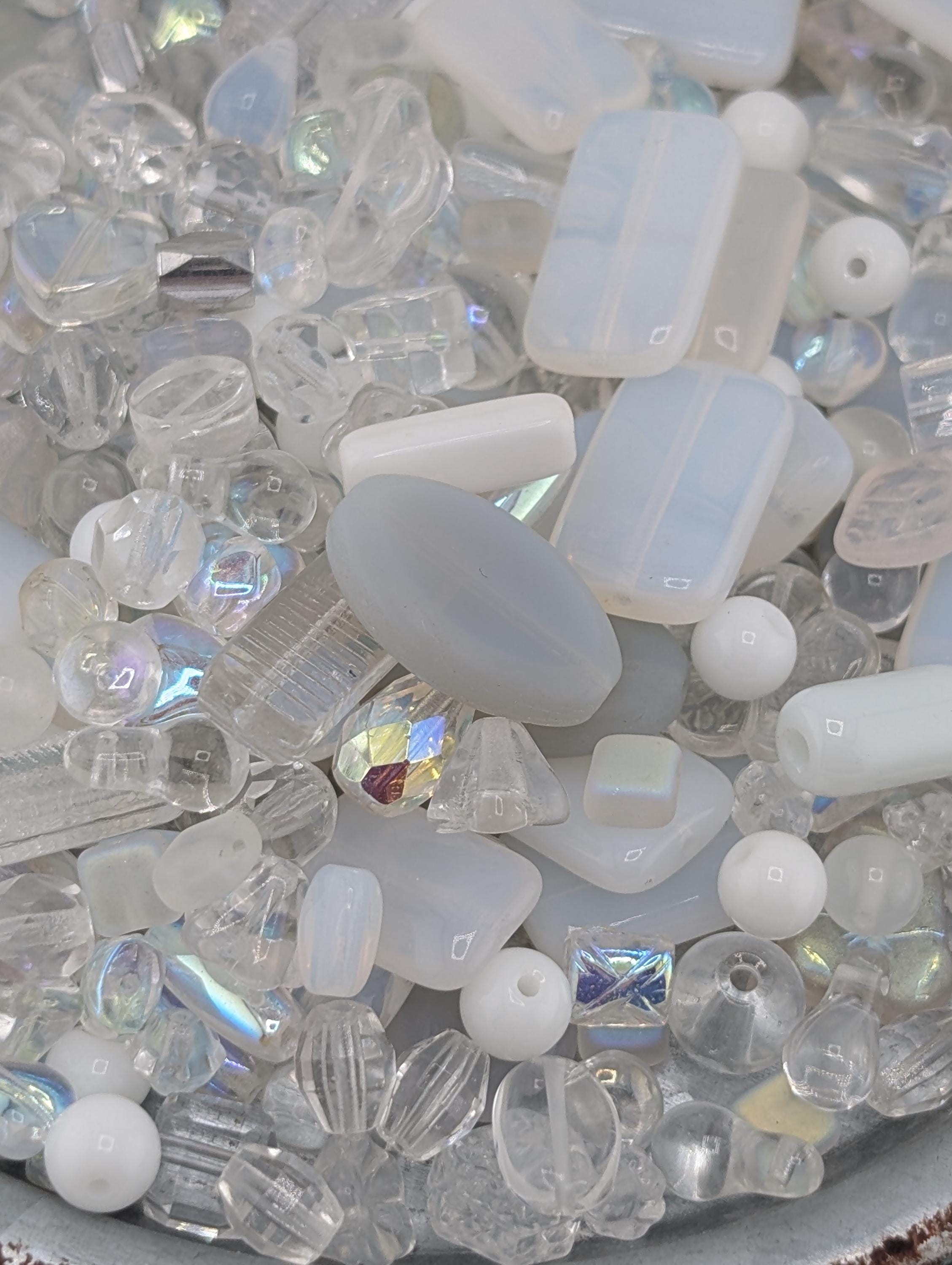 a variety of clear glass beads and crystals, including round, square, and rectangular shapes, scattered together in a visually appealing manner.