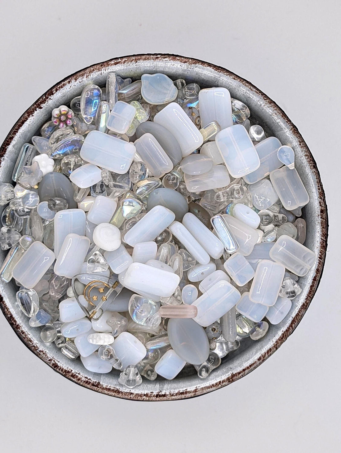 a variety of clear glass beads and crystals, including round, square, and rectangular shapes, scattered together in a visually appealing manner.