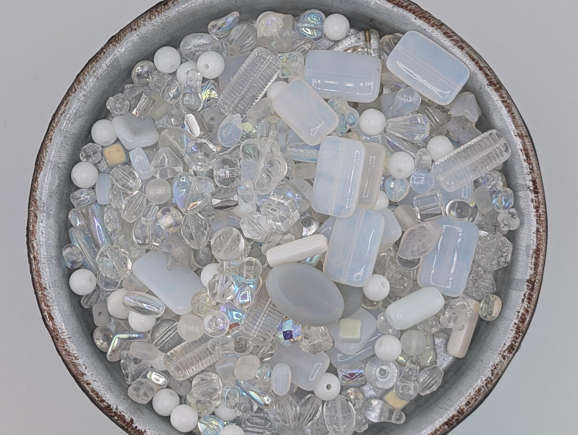 A bowl filled with various clear glass beads and crystals, including clear beads, clear crystals, and clear glass beads.