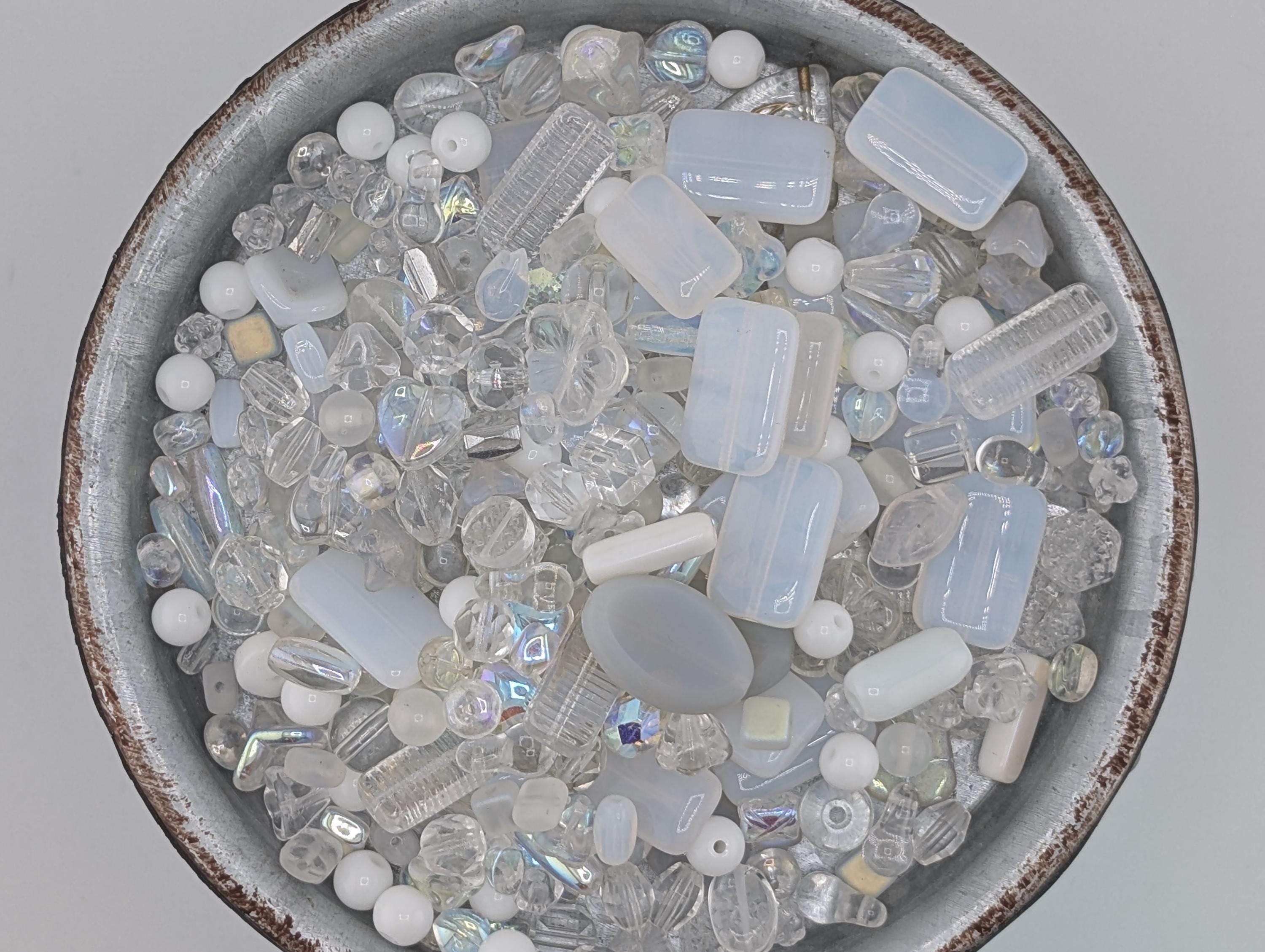 A bowl filled with various clear glass beads and crystals, including clear beads, clear crystals, and clear glass beads.