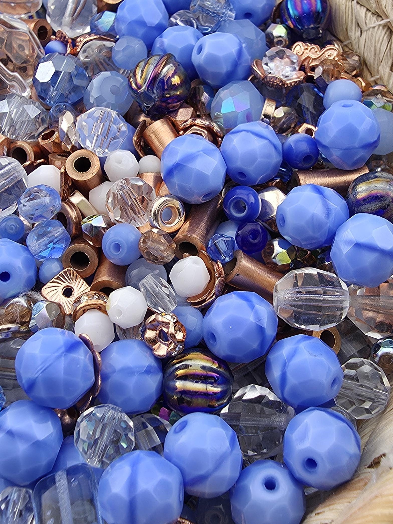 A close-up image of various colored beads, including blue, clear, and multicolored beads, scattered together.
