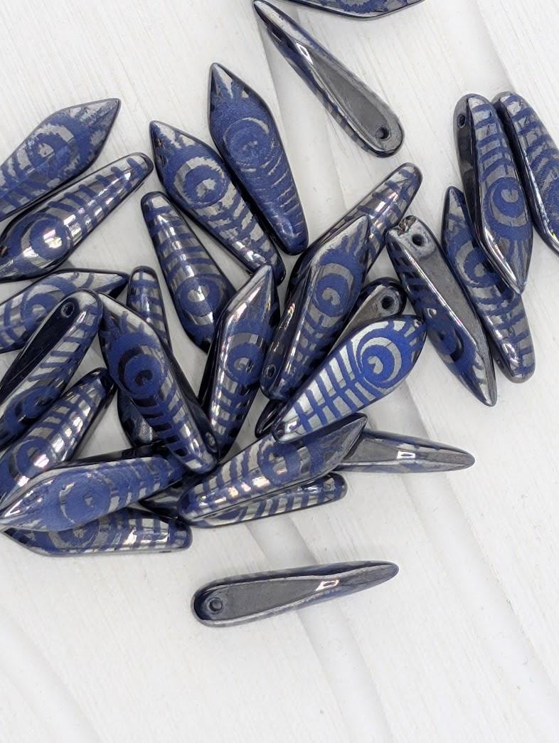 a collection of blue and silver beads with intricate designs, scattered on a white surface.