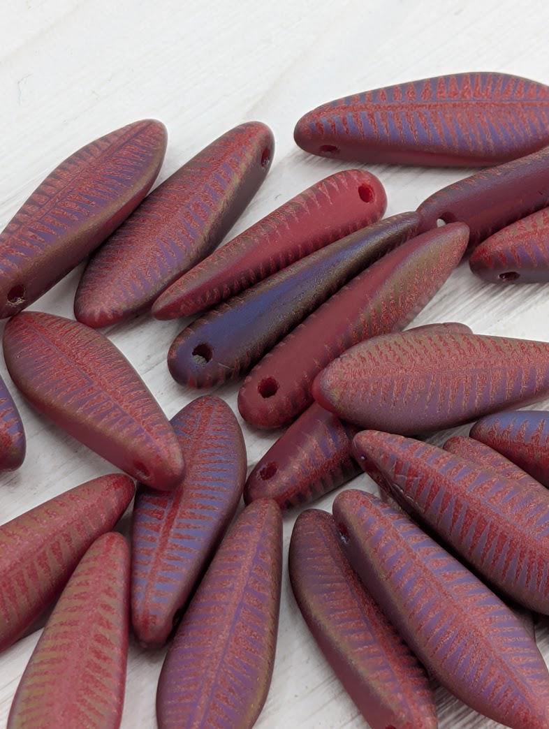 a collection of red and purple beads arranged on a white surface.