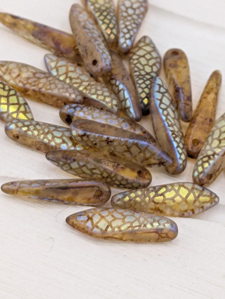 a collection of various beads, including some with a diamond pattern, scattered on a white surface.