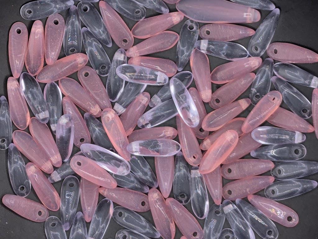 numerous small, clear beads in shades of pink and purple, scattered across a dark background.
