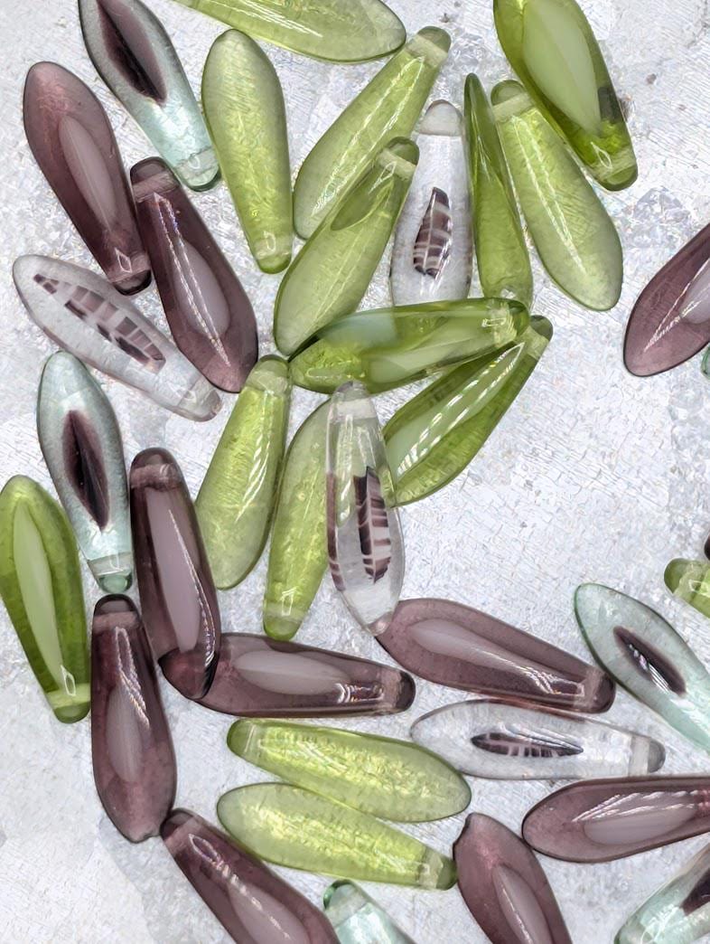 a collection of various colored glass beads, including green, purple, and clear beads, arranged in a visually appealing manner.