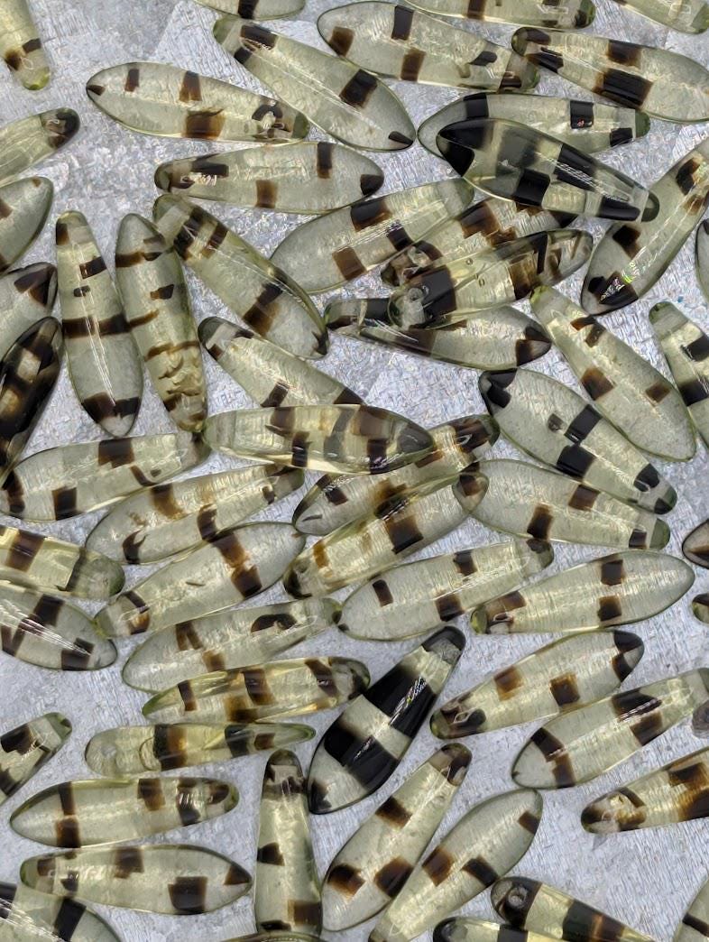 a collection of small, clear beads with a striped pattern, scattered across a surface.