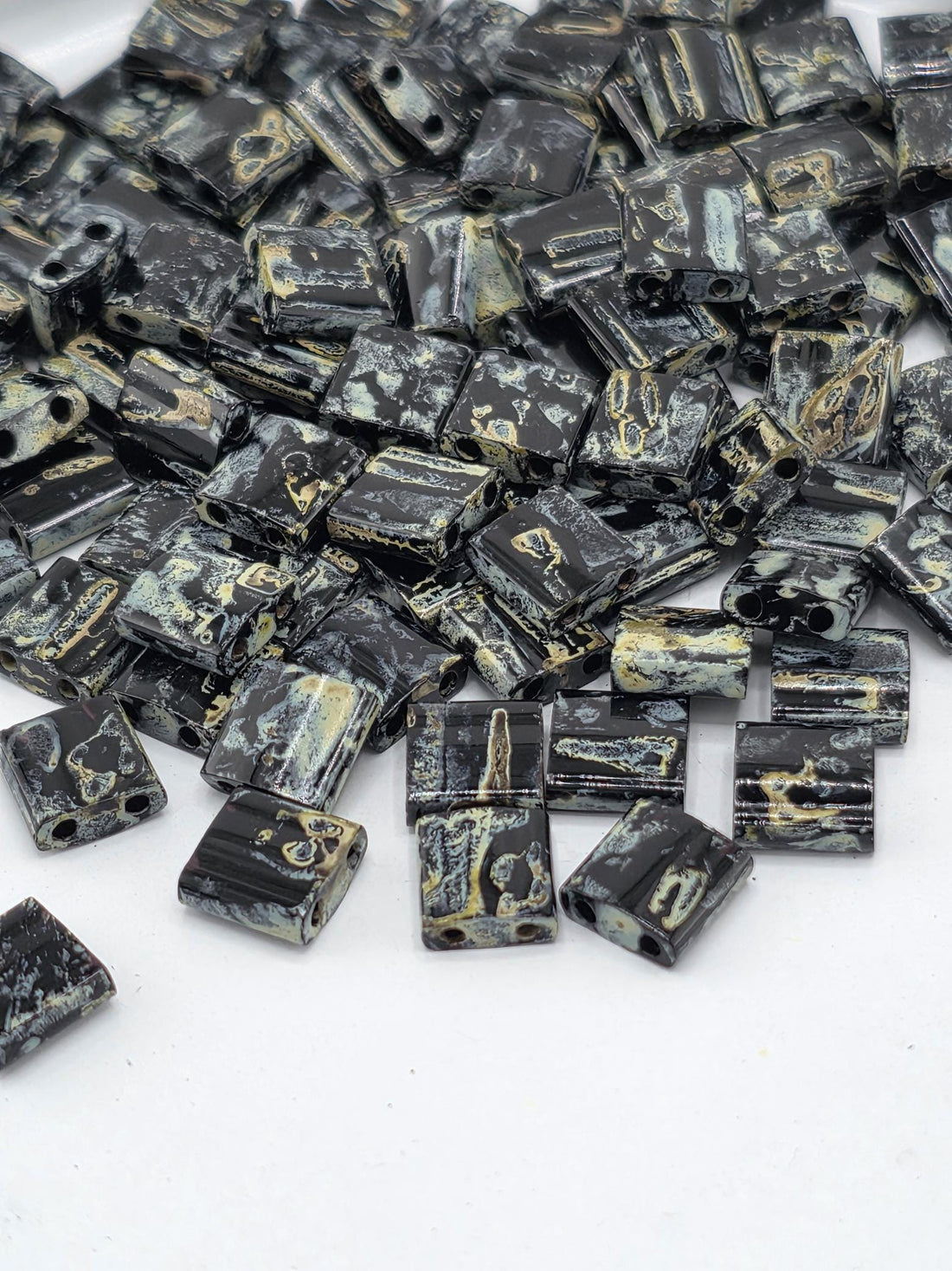 a collection of black and gold beads scattered on a white background.