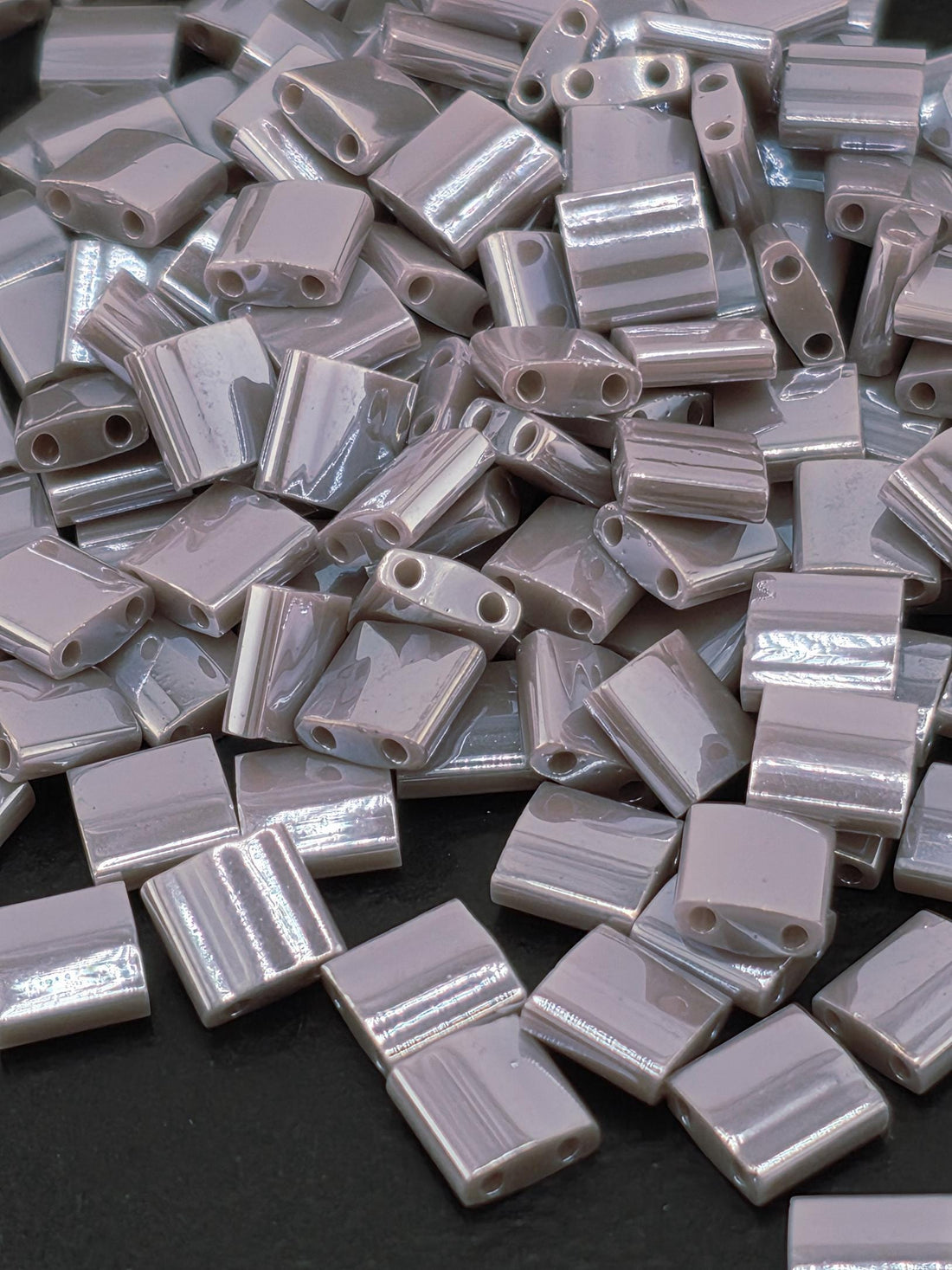 The image is a close-up of numerous small, rectangular, metallic objects with a shiny, reflective surface.