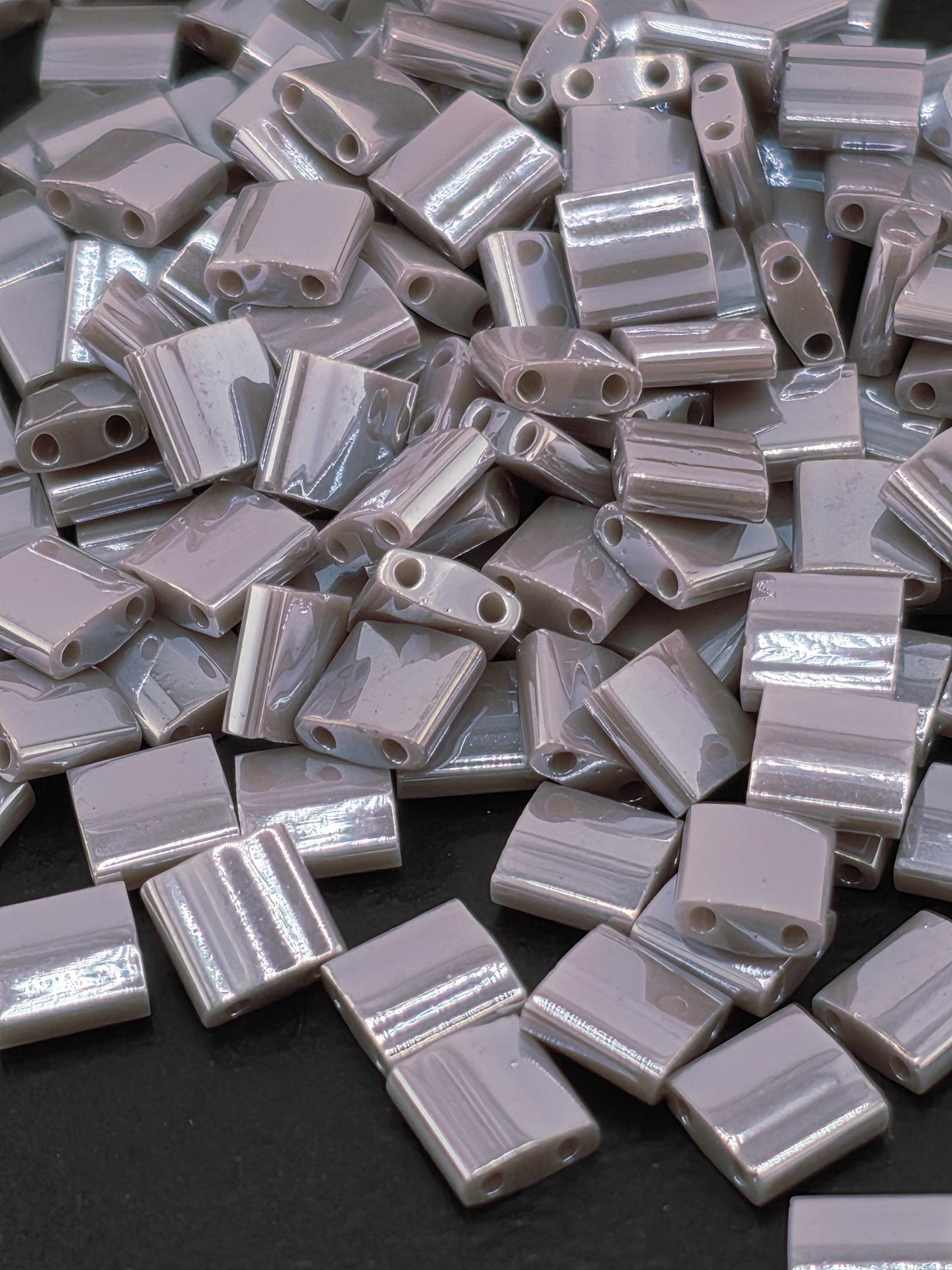 The image is a close-up of numerous small, rectangular, metallic objects with a shiny, reflective surface.
