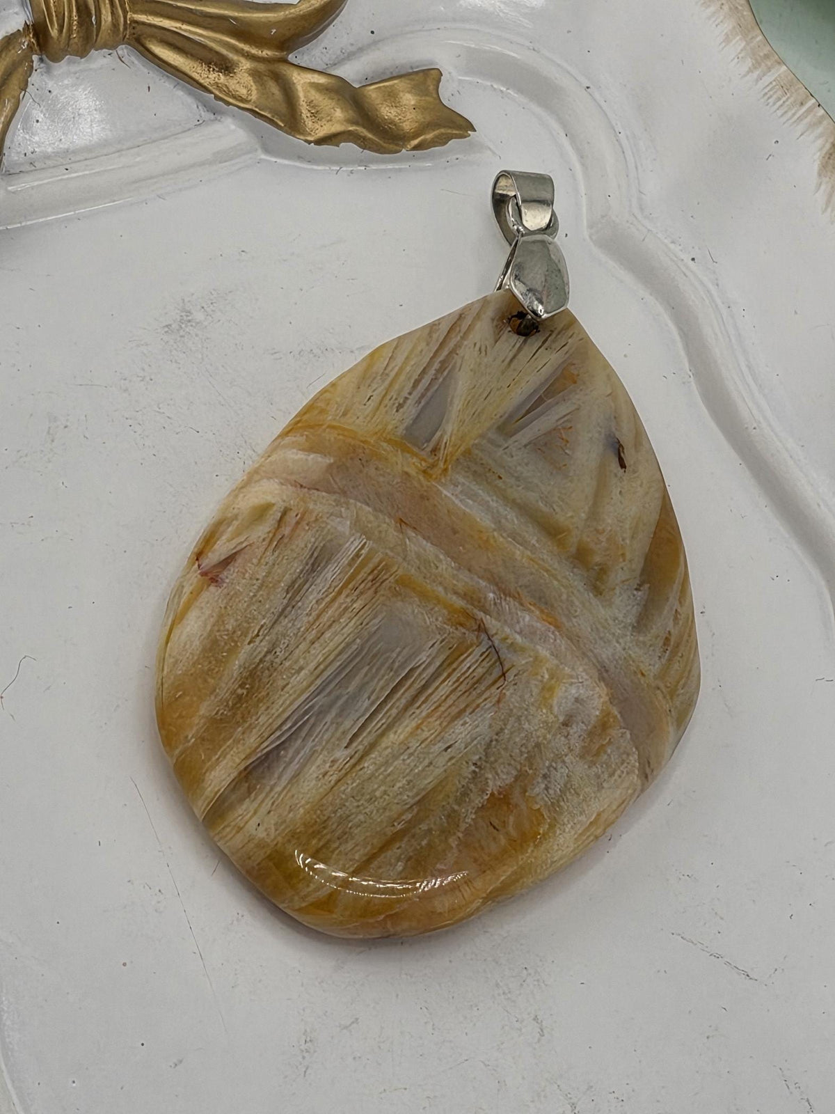A pendant made of a large, irregularly shaped stone with a metallic clasp attached to it.
