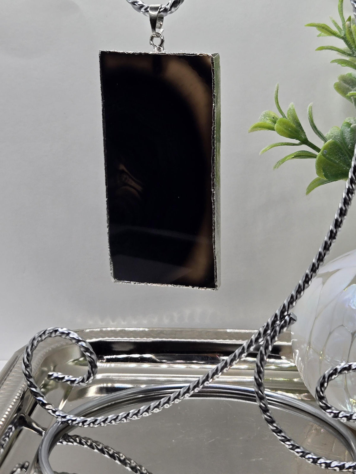 a black rectangular object with a silver chain hanging from it, placed on a white surface.
