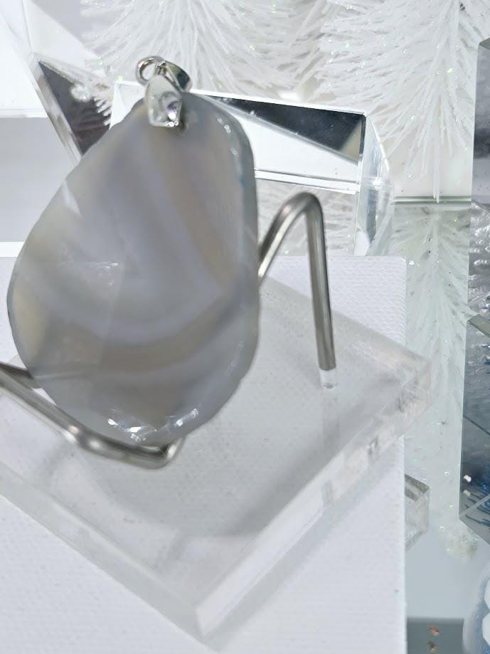 a clear glass stand holding a large, irregularly shaped stone or gemstone.