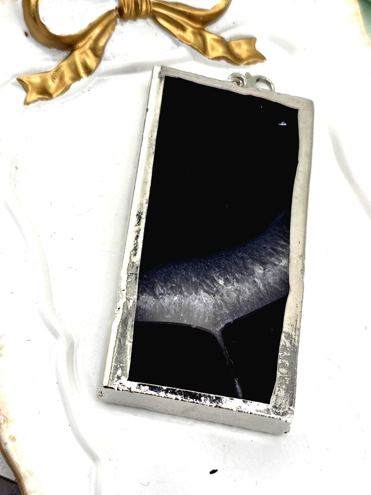 a rectangular, black-colored object with a silver frame, placed on a white surface.