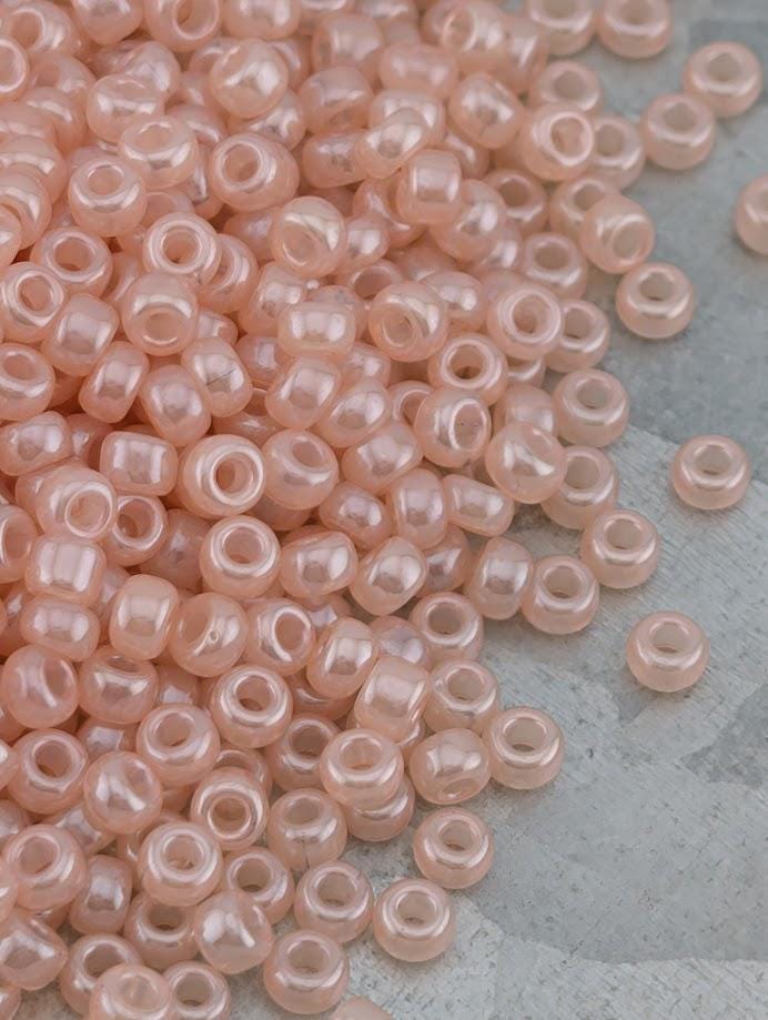 A pile of small, clear beads in various shades of pink, scattered on a gray surface.