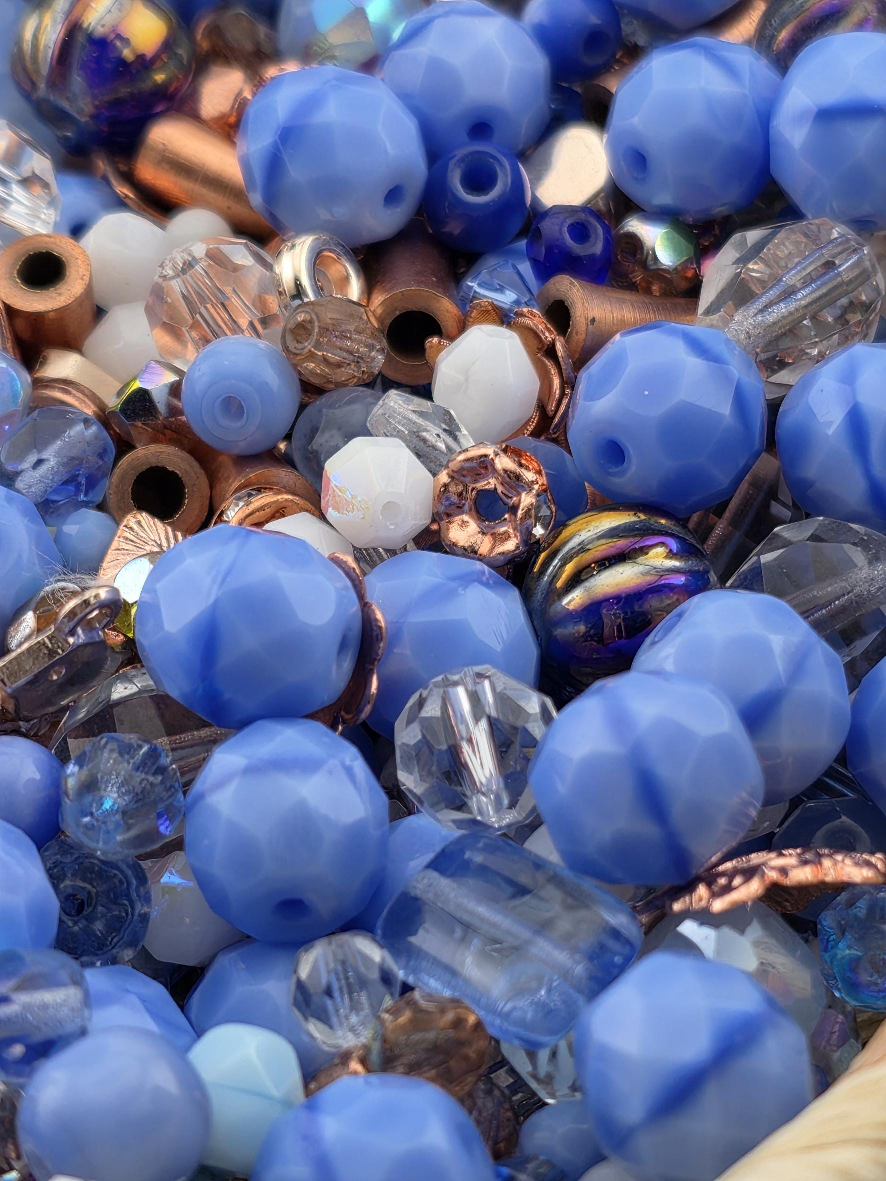The image is a close-up of various blue and copper-colored beads, including clear and multicolored beads, arranged in a visually appealing manner.