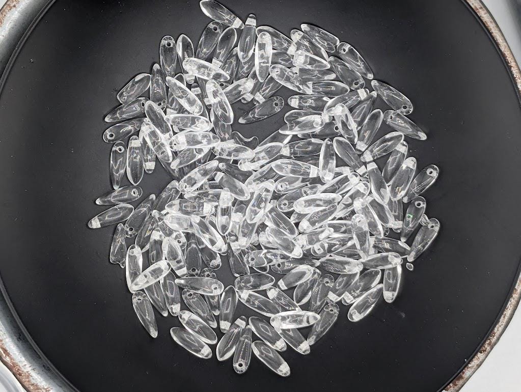 A black plate filled with numerous clear glass beads, creating a visually striking and intricate arrangement.