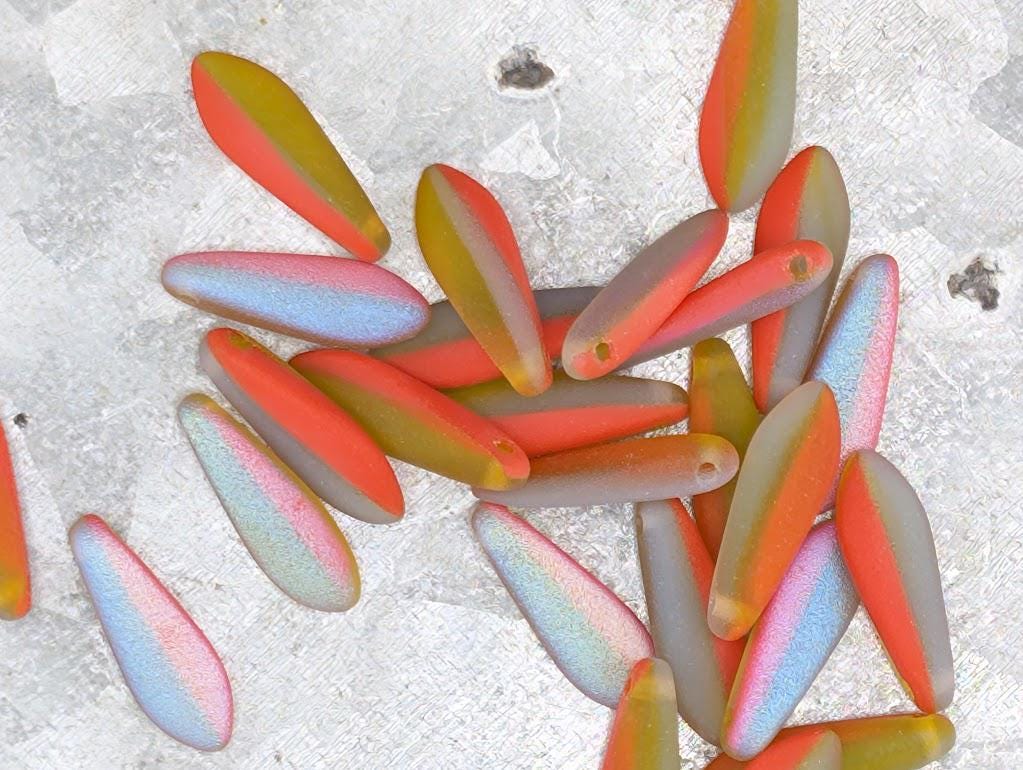 a collection of colorful, multicolored glass beads or stones scattered on a textured surface.