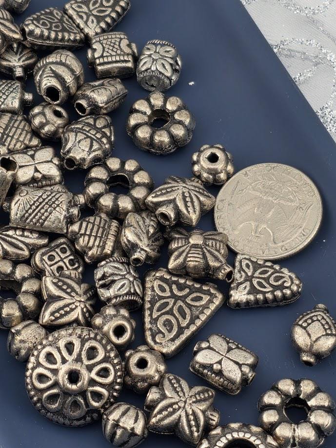 a collection of various metal beads and charms scattered on a blue surface.