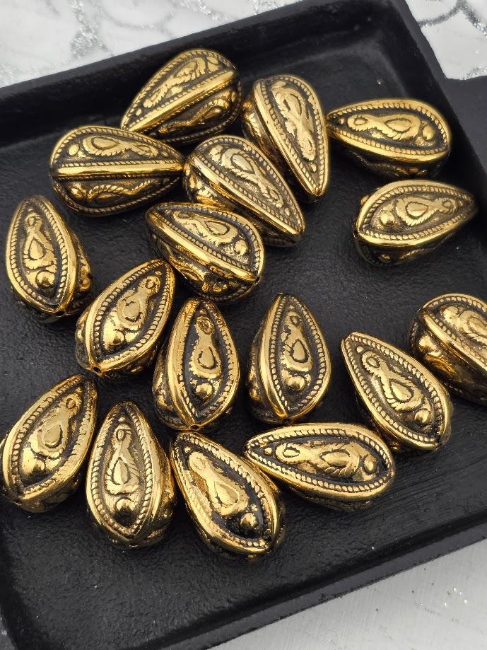 a collection of ornate, golden-colored metal beads or coins arranged on a black surface.