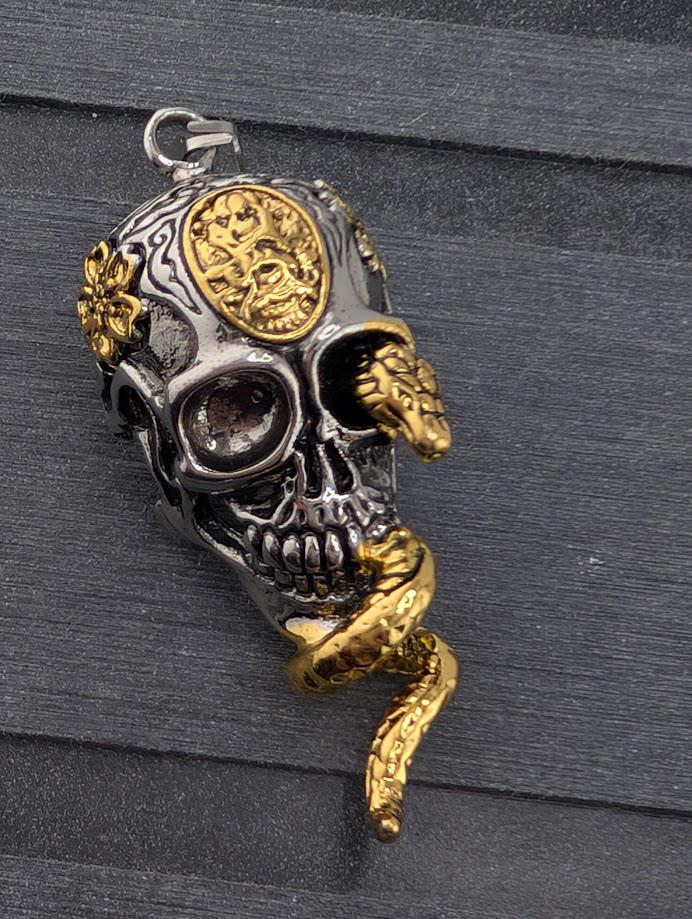 A pendant in the shape of a skull with a snake wrapped around it, set against a dark background.