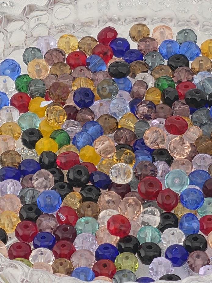 The image is a close-up of a collection of colorful glass beads, including various shapes and sizes, arranged in a visually appealing manner.