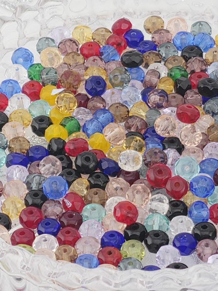 The image is a close-up of a collection of colorful glass beads, including various shapes and sizes, arranged in a visually appealing manner.
